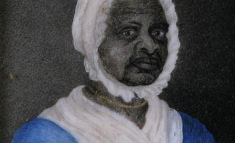 一个黑人妇女的肖像，她穿着一件蓝色的裙子，脖子和腰上系着细绳, 一条白色的围巾塞在她的裙子的脖子上, a white cap, 还有一条金串珠项链.